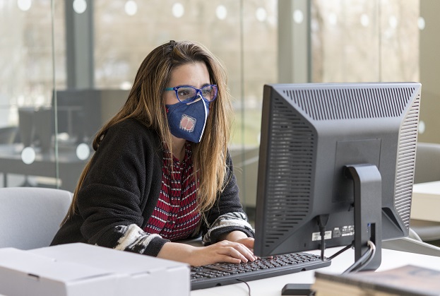 woman at desktop computer with Covid-19 facemask